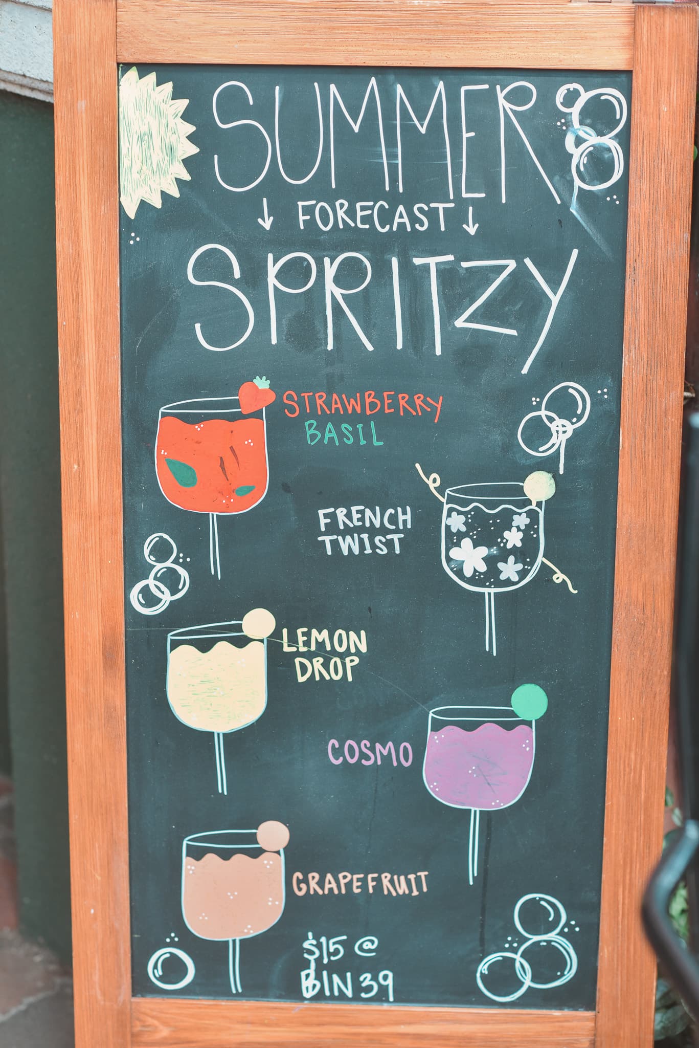 Chalkboard menu listing summer cocktails: Strawberry Basil, French Twist, Lemon Drop, Cosmo, and Grapefruit, priced at $15 each.