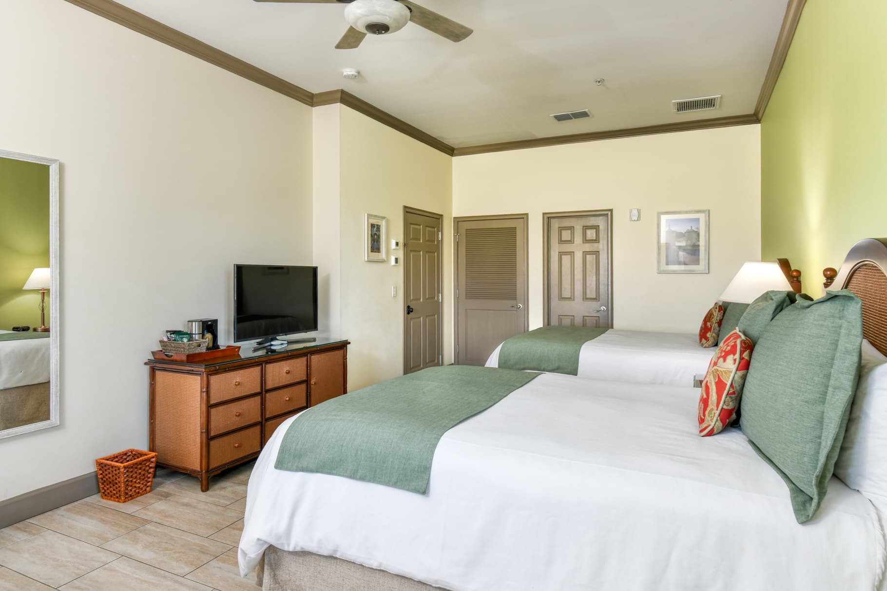 A cozy hotel room featuring two beds, a TV, and a dresser.