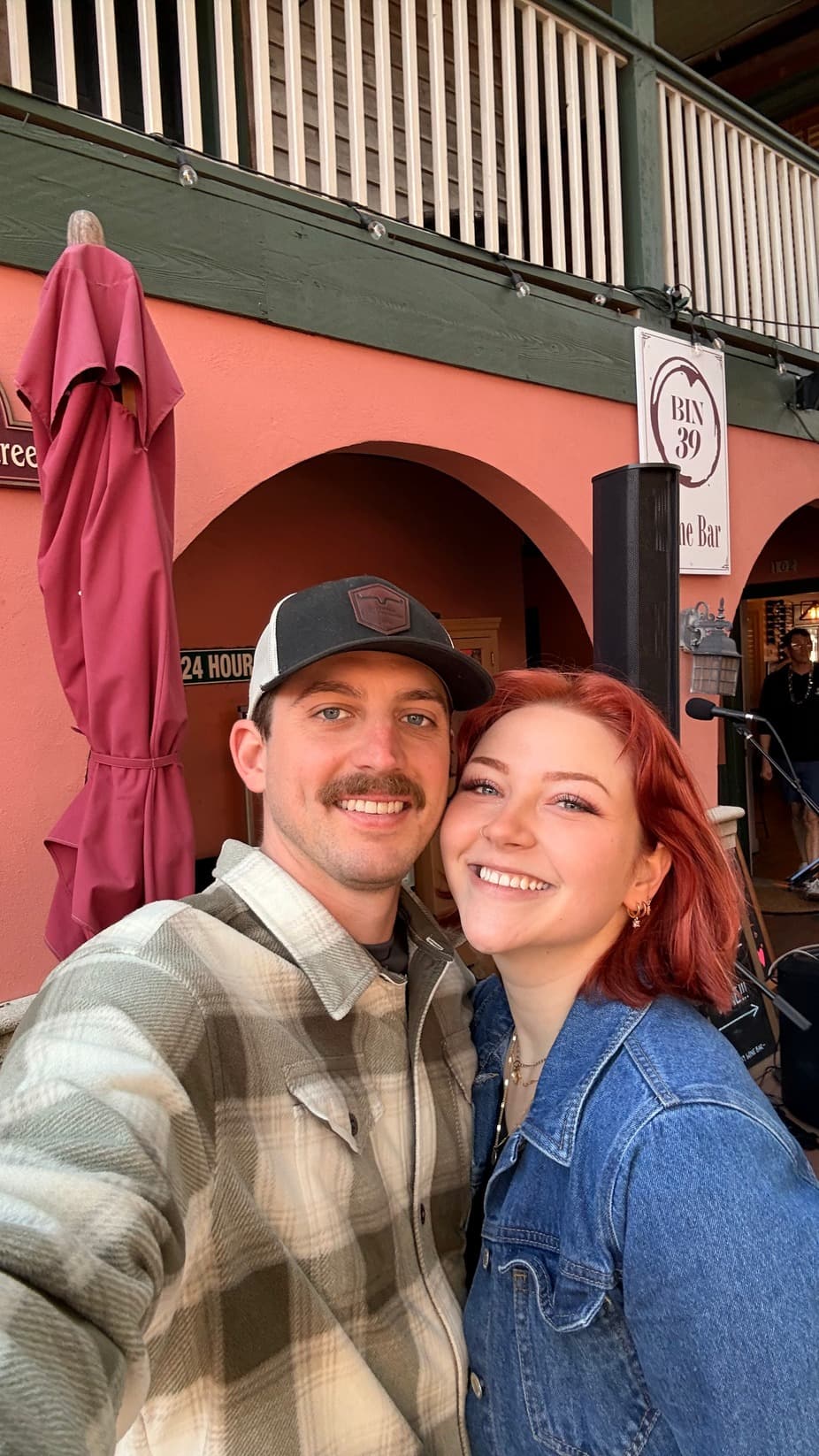 A smiling couple poses for a selfie in a colorful setting.