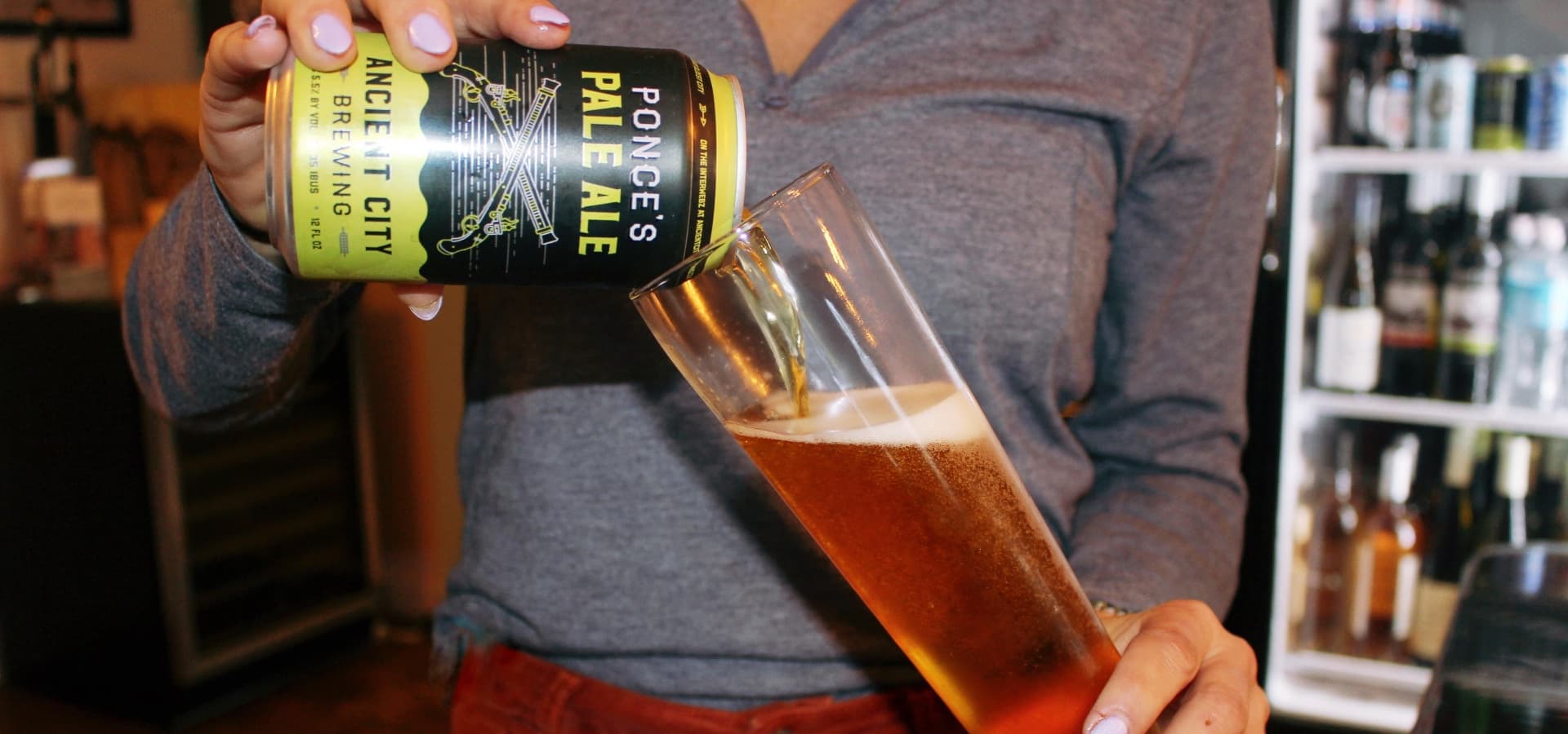 A person pours a can of Ponce's Pale Ale into a glass. A person pours a can of Ponce's Pale Ale into a glass.