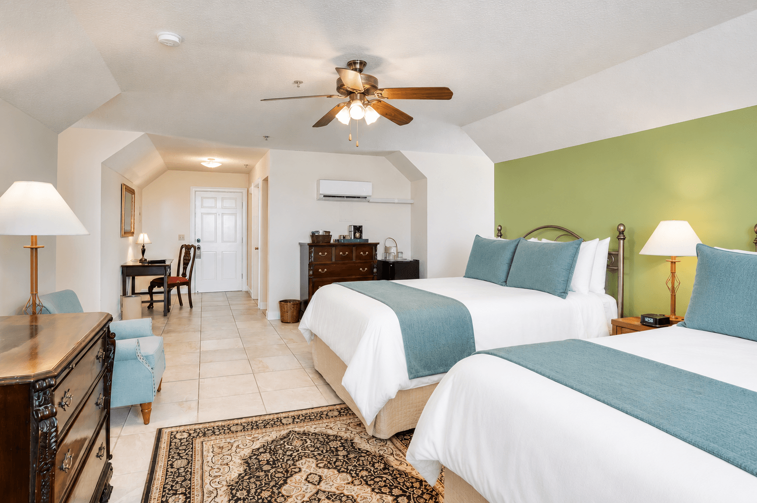 A spacious hotel room featuring two beds, a dining area, and stylish decor.