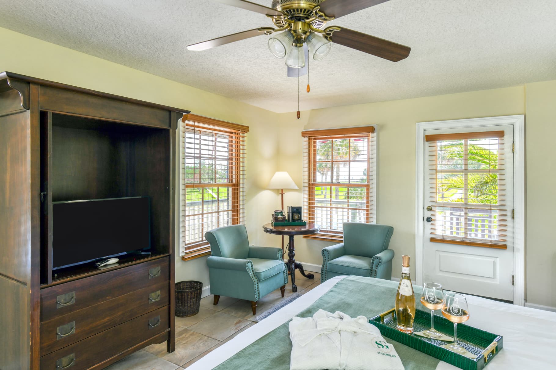 Cozy bedroom with a TV, two armchairs, and a door leading to an outdoor area.