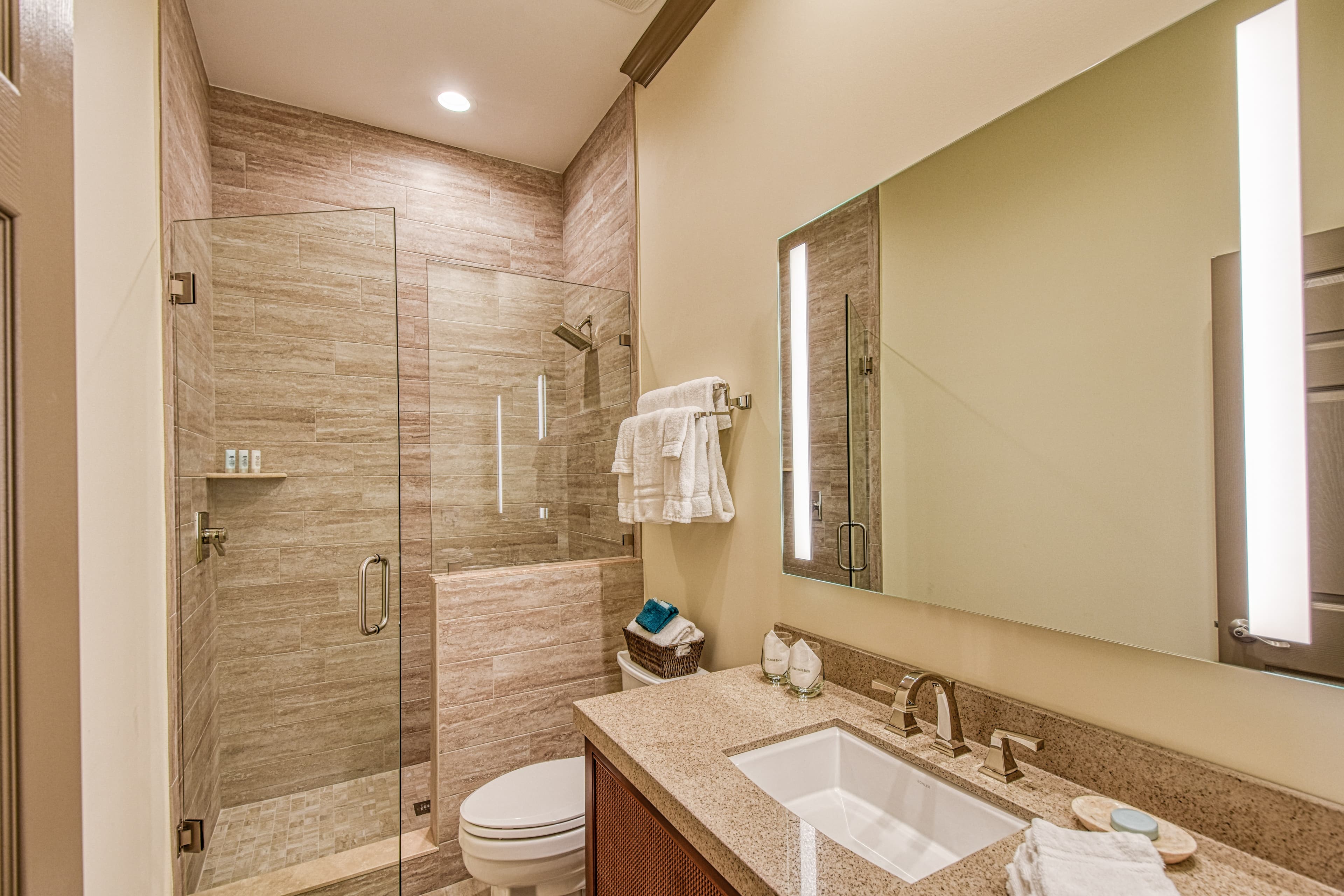 A modern bathroom featuring a glass shower, sink with countertop, and stylish lighting.