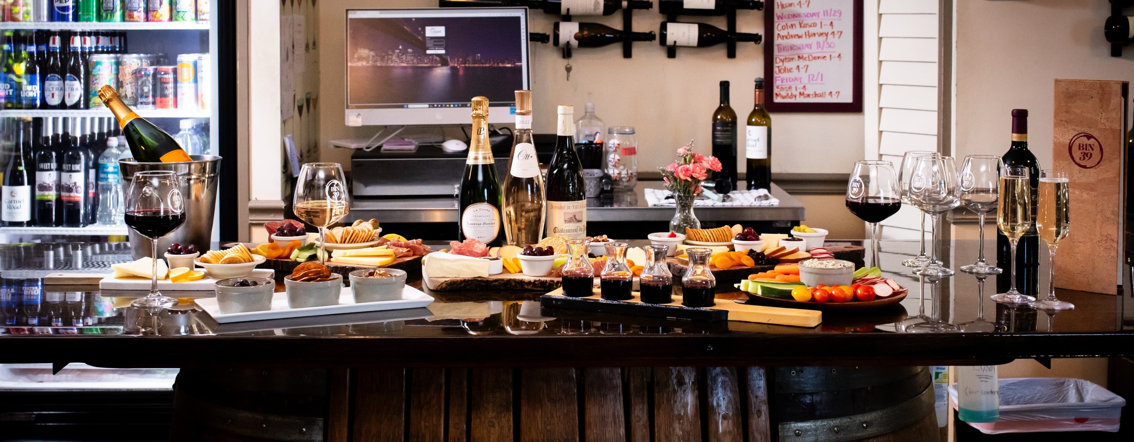 A stylish bar setting displays an array of wines and gourmet appetizers on a wooden counter.