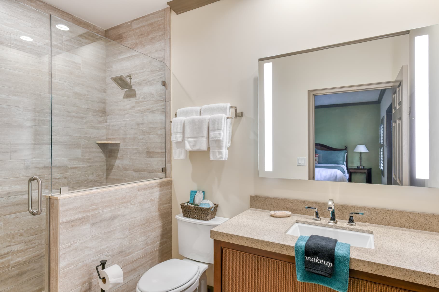 A modern bathroom featuring a glass shower, a sink with a wooden vanity, and neatly arranged towels.