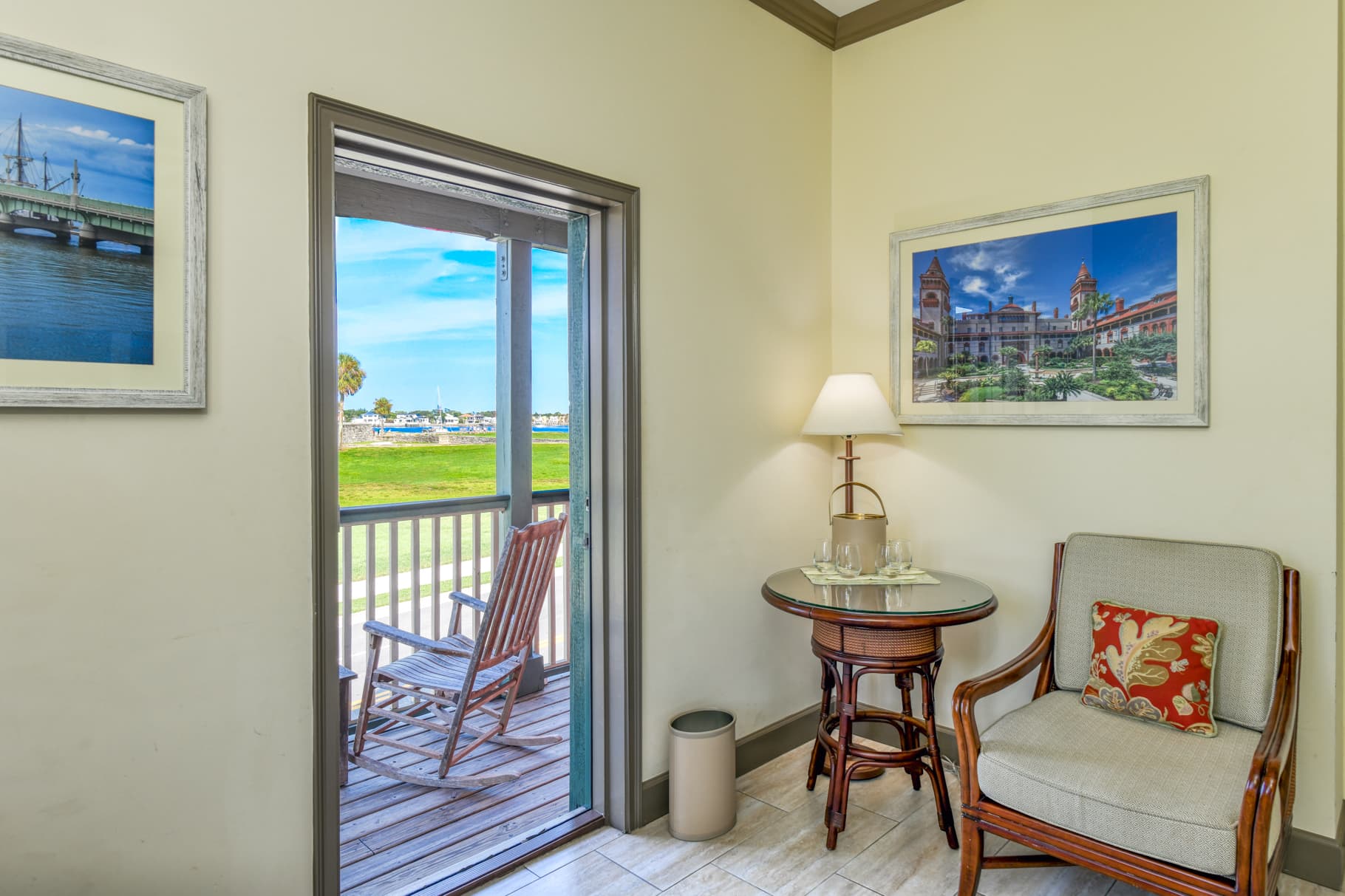 A cozy interior corner features a chair, side table, lamp, and an open door leading to a scenic outdoor view.