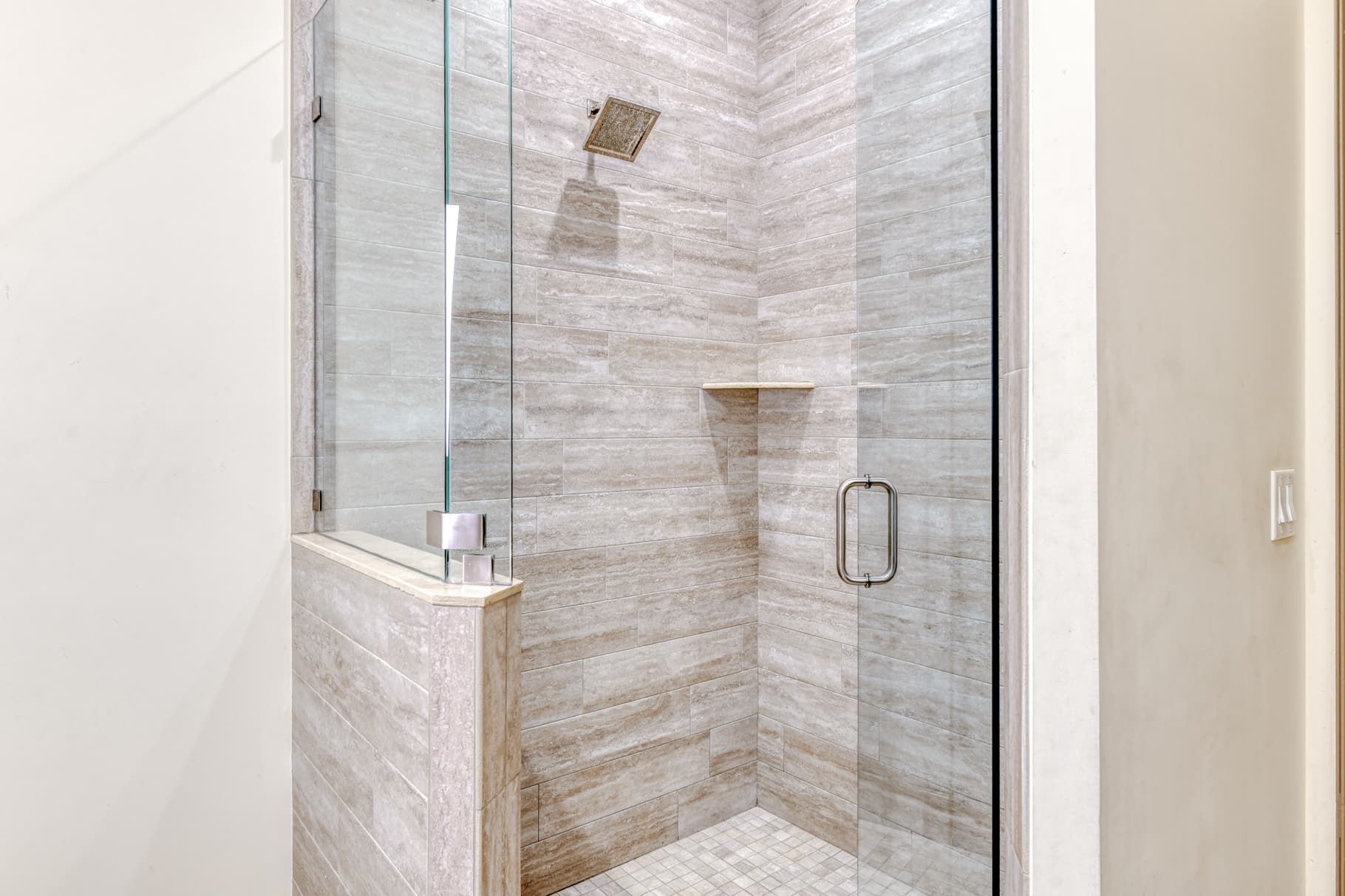 Modern glass shower enclosure with textured stone walls and a minimalist design.