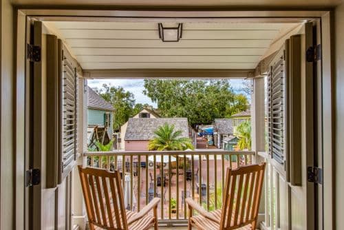 A cozy balcony view with two rocking chairs overlooking a picturesque courtyard and greenery.