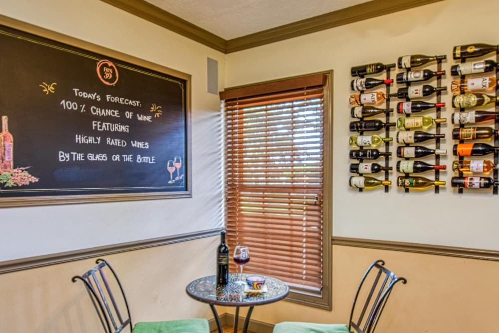 A cozy wine corner features a chalkboard with a whimsical forecast and a wall displaying various wine bottles.