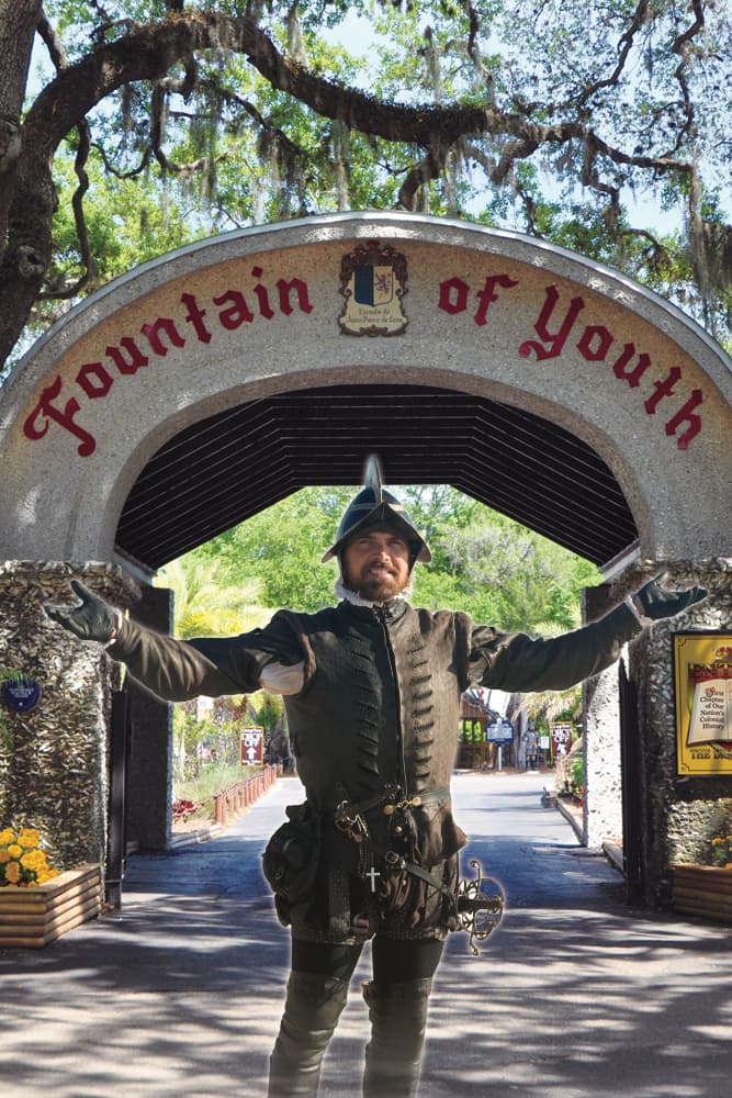 A man in historical attire stands with outstretched arms at the entrance of the Fountain of Youth.