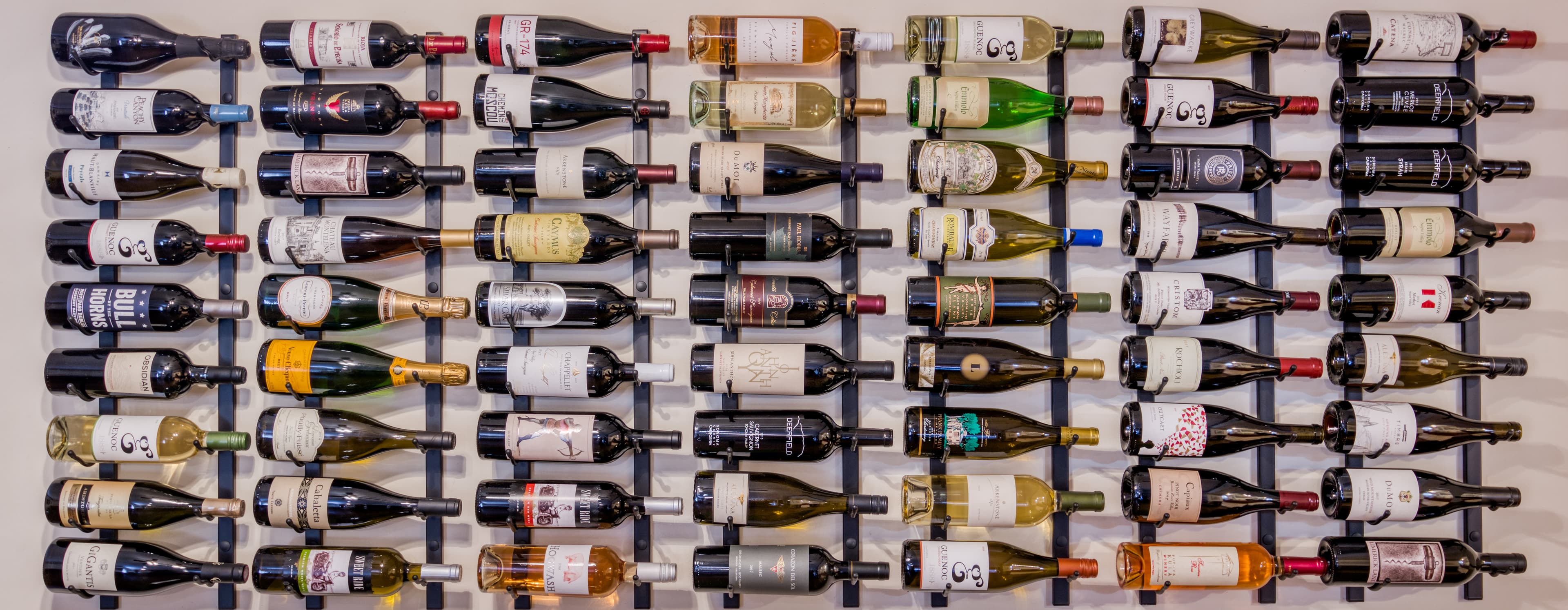 A wall-mounted wine rack displaying a variety of wine bottles.