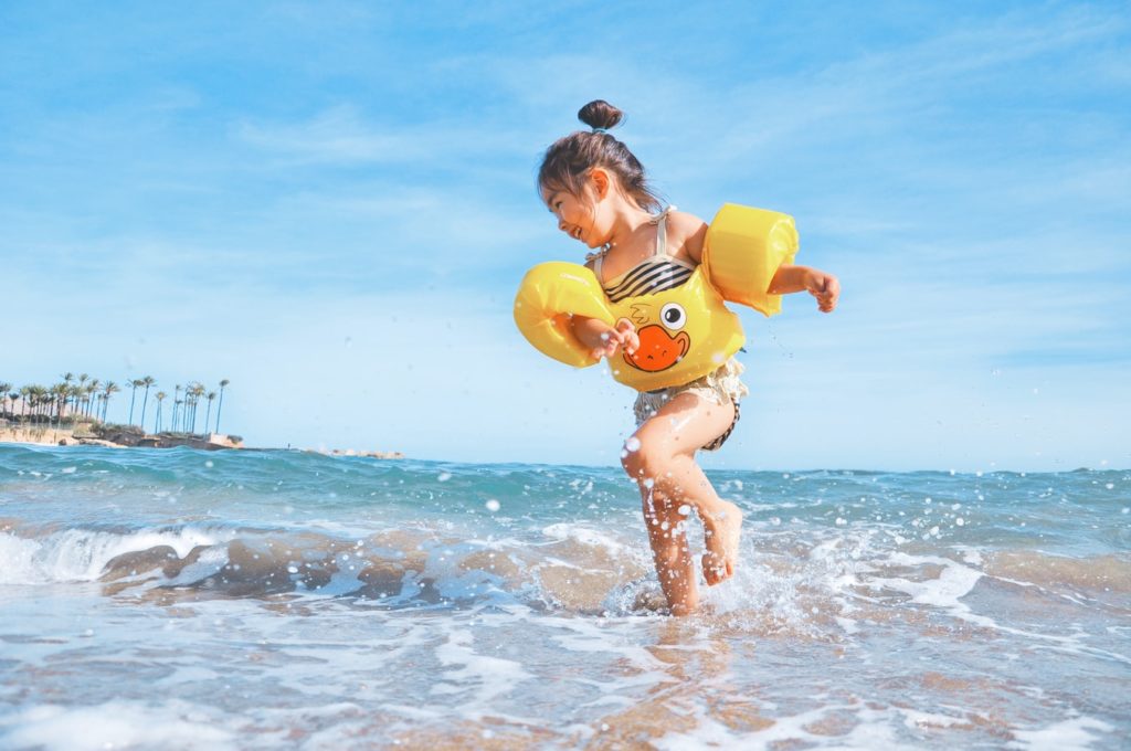 Young girl playing in the water with duck floaties on