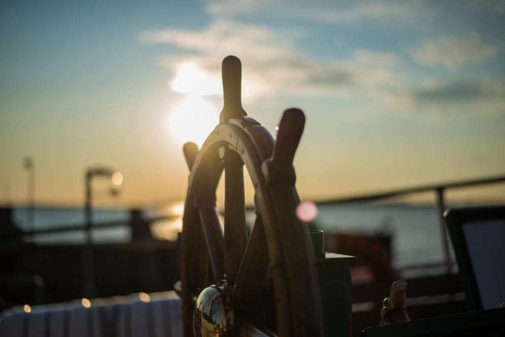 Boat steering wheel backlit by a sunset